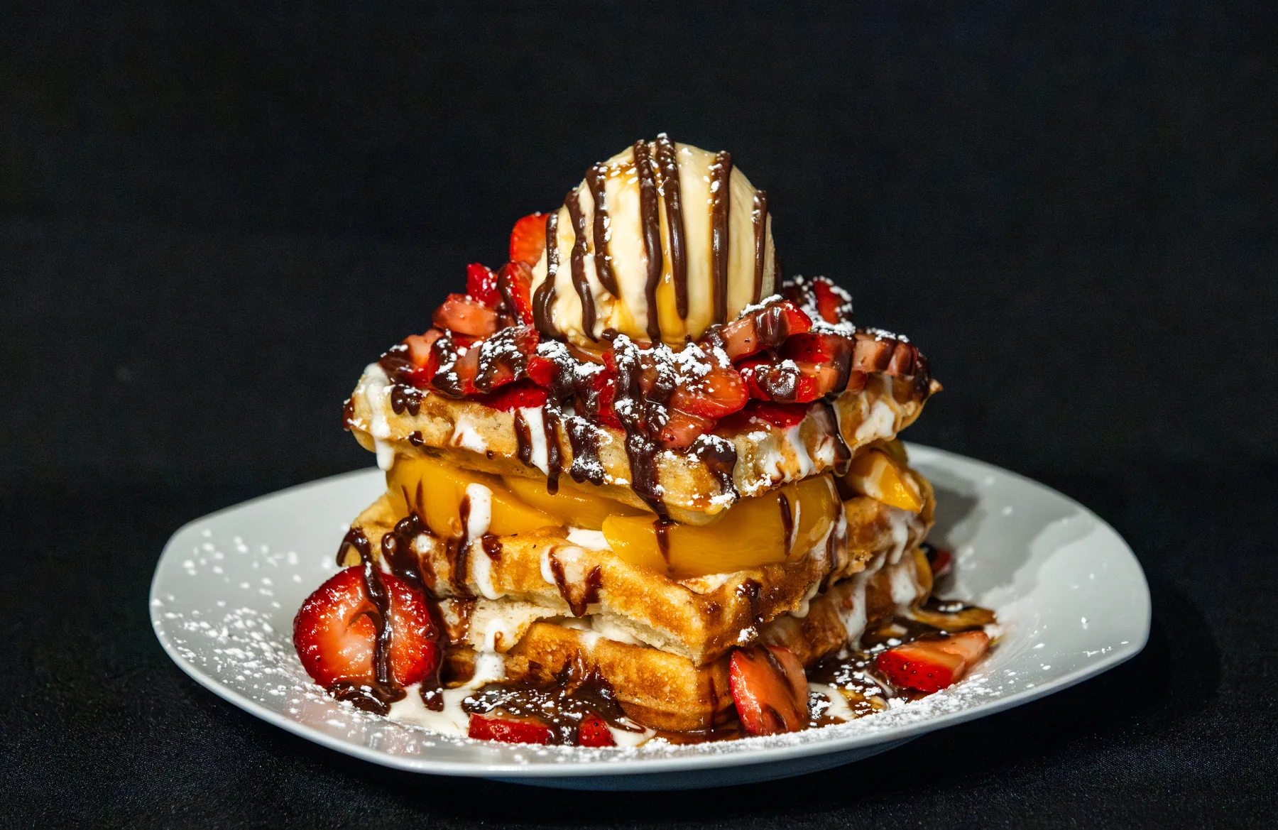 Sweet waffle topped with berries, ice cream, and whipped cream