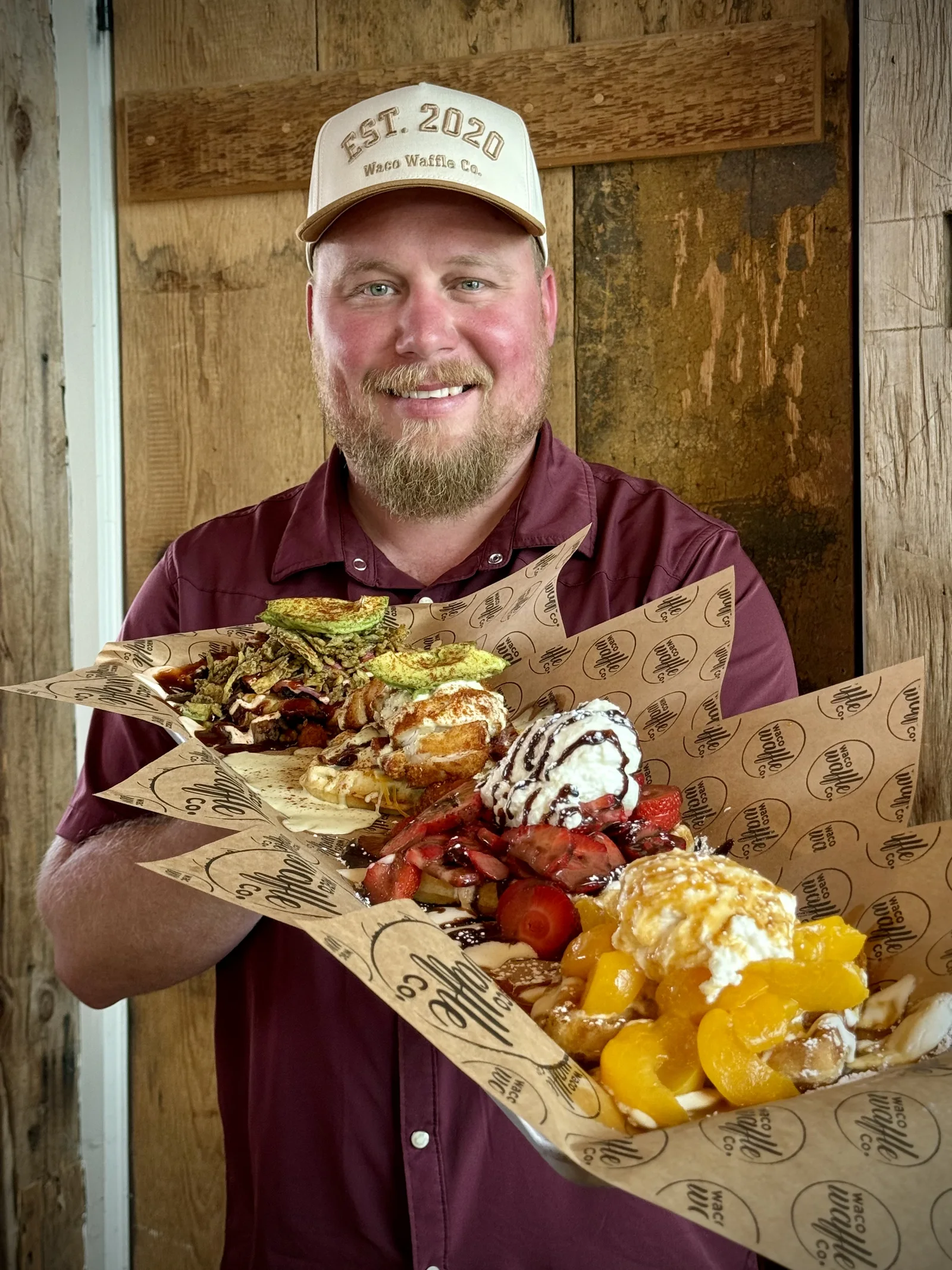 Smiling Waco Waffle Co. team member presenting a fresh sandwich