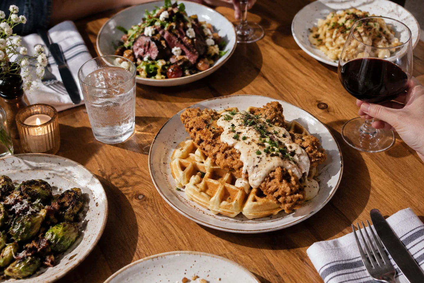 Chicken and waffles dinner spread on a wooden table at Waco Waffle Co.
